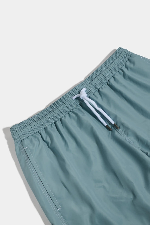 Teal shorts with a white drawstring on a light gray background