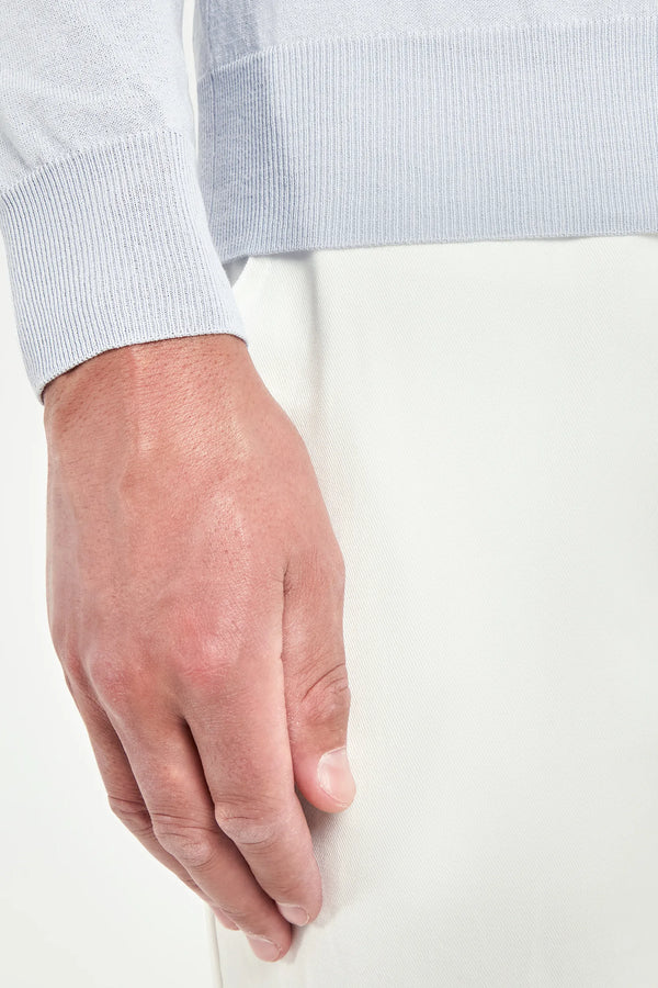 Close-up of a person's hand holding a white object against a light background