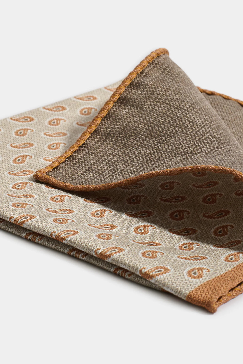 Two patterned cloths, one beige with brown paisley design and the other brown with beige paisley design, on a white background.